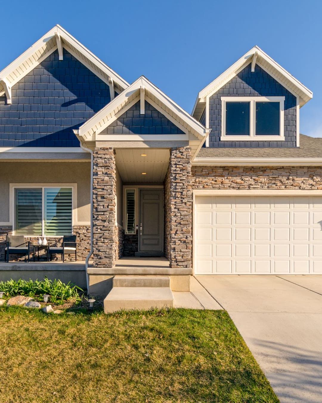 Craftsman-style home exterior with a stone porch under a blue sky